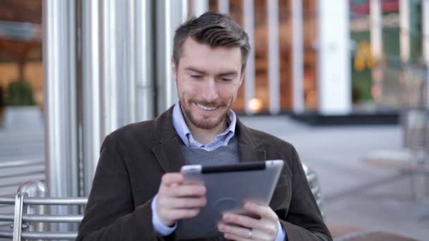 Bel homme en utilisant un ordinateur tablette près du centre d'affaires moderne, gratte-ciel, centre commercial (slider shot ) — Video