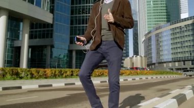 Yakışıklı adam akıllı telefon kulaklık müzik dinlemek ve gökdelenler dans