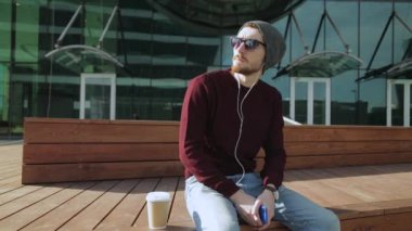 Yakışıklı hipster ahşap Bank smartphone kulaklıktan müzik