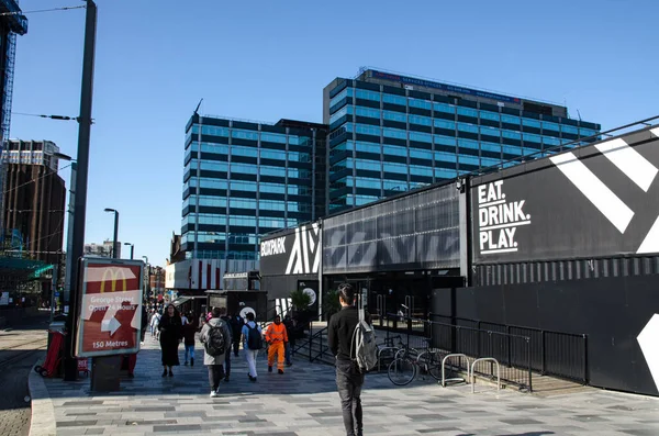 Croydon, İngiltere - 2 Ekim 2019: Güney Londra 'da güneşli bir sonbahar sabahında Doğu Croydon' daki Boxpark imalathanesinin yiyecek ve baro hizmetlerinden geçen yayalar.