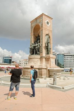 ISTANBUL, TURKEY - 5 Haziran 2016: İstanbul, Taksim Meydanı 'nda güneşli bir sabahta heybetli Cumhuriyet Anıtı' na bakan turistler.