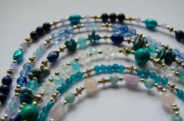 Gül kuvarsı, jasper, apatit, ametist, lapis lazuli ve incileri içeren yarı değerli taşlardan yapılmış bir kolye koleksiyonu. Gümüş kaplama boncuklarla ayrılmış çeşitli boncuklar..  