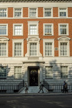 LONDON, İngiltere - 25 Temmuz 2017: Birinci Dünya Savaşı sırasında ABD Büyükelçisi Walter Hines Page 'in evi olan Grosvenor Meydanı' ndaki görkemli ofis ve apartman bloğunun yanından geçen ofis çalışanları. 