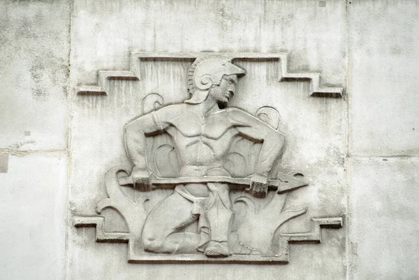 Sculpted stone relief of the Roman god of fire Vulcan.  On the facade of the 1930\'s building which once house the headquarters of the British Iron and Steel Federation on Tothill Street, Westminster, London.  Sculpted in Portland stone by William Aum