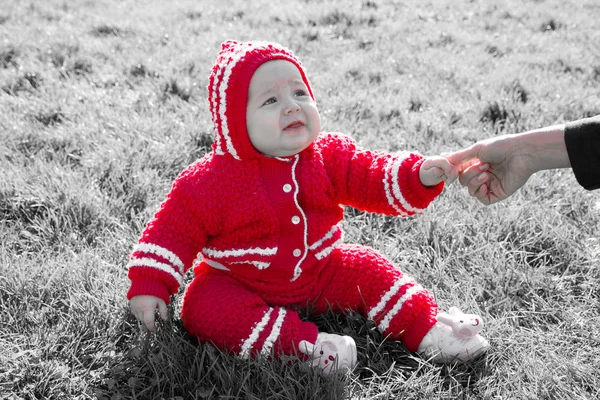 Little baby sitting on the grass. Mom holding the baby by the arm — Stock Photo, Image