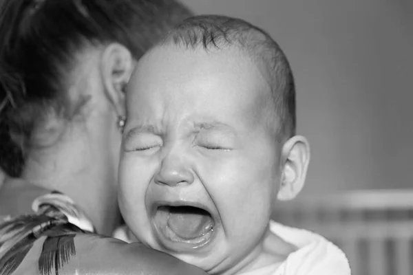 Mamá alivia al bebé. El bebé está llorando. —  Fotos de Stock