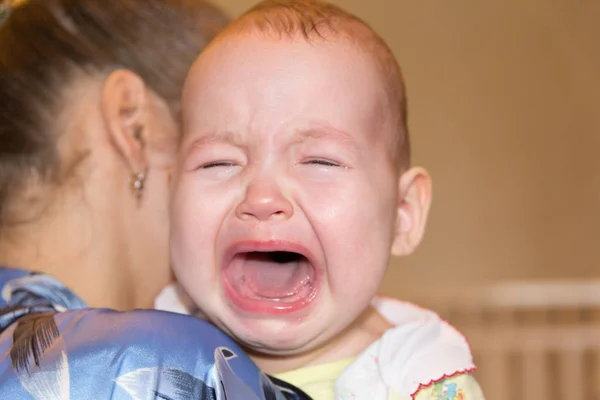 Mamá alivia al bebé. El bebé está llorando. —  Fotos de Stock