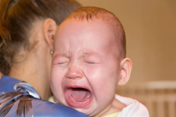 Mamá alivia al bebé. El bebé está llorando. —  Fotos de Stock