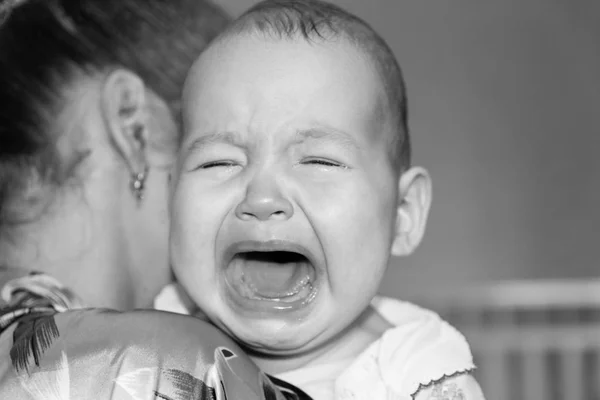 Mamá alivia al bebé. El bebé está llorando. —  Fotos de Stock