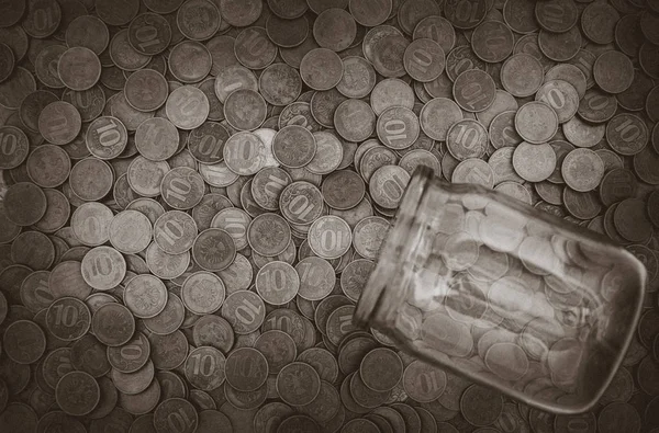 Un montón de monedas y un frasco de vidrio —  Fotos de Stock
