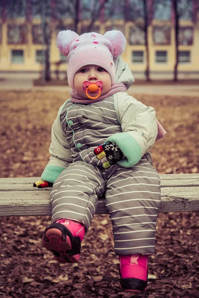 Baby with a pacifier sitting on a bench — Stock Photo, Image