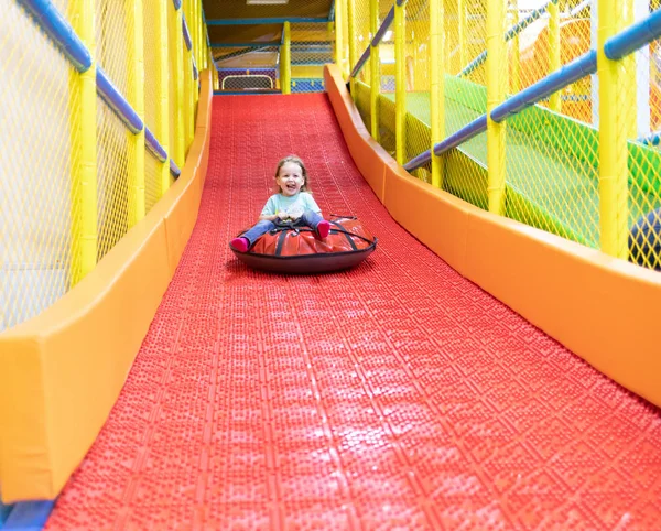 Child quickly rolls down the hill in the play center — Stock Photo, Image