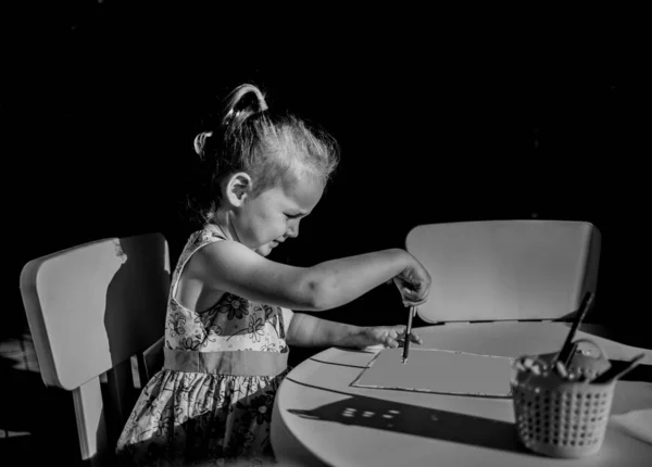 Niño talentoso dibuja y pinta cuadros en blanco y negro — Foto de Stock