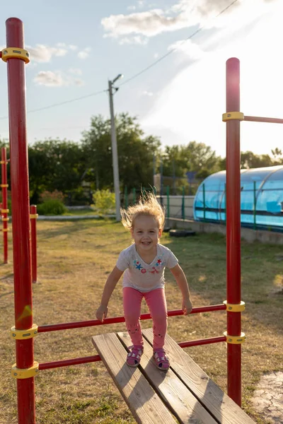 Un niño pequeño va a practicar deportes en el estadio. colgando en la barra horizontal, en las barras irregulares —  Fotos de Stock