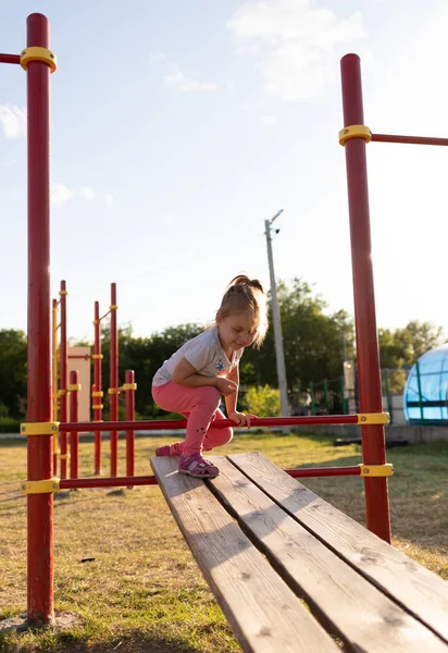 Un niño pequeño va a practicar deportes en el estadio. colgando en la barra horizontal, en las barras irregulares —  Fotos de Stock