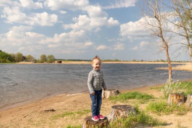 Çocuk bir kütüğün üzerinde duruyor, uzaklığa bakıyor.