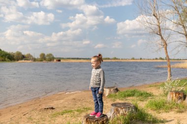 Çocuk bir kütüğün üzerinde duruyor, uzaklığa bakıyor.