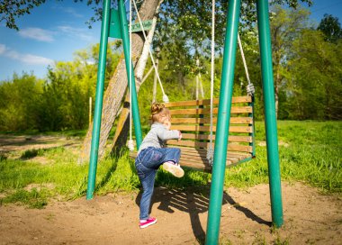 Çocuk salıncak sallıyor. Çocuk salıncakta oturuyor