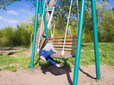 Çocuk salıncak sallıyor. Çocuk salıncakta oturuyor