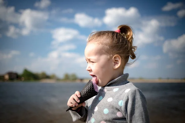 Child eats ice cream in a black waffle cone — Stock Photo, Image