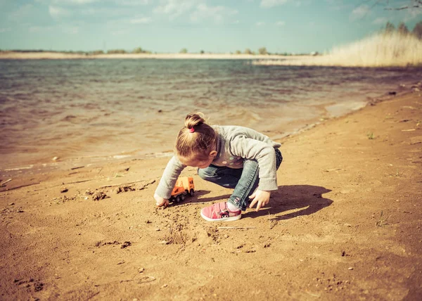 Niño juega con camión de juguete en la playa — Foto de Stock