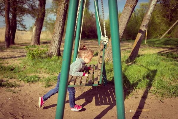 Niño balanceando un columpio. niño sentado en un columpio —  Fotos de Stock