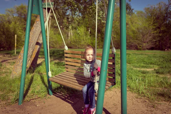 Niño balanceando un columpio. niño sentado en un columpio —  Fotos de Stock