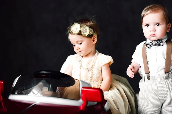 Dos bebés boda - niño y niña vestido como novia y novio jugando con coche de juguete — Foto de Stock