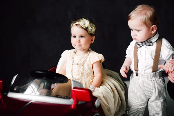 Dos bebés boda - niño y niña vestido como novia y novio jugando con coche de juguete — Foto de Stock