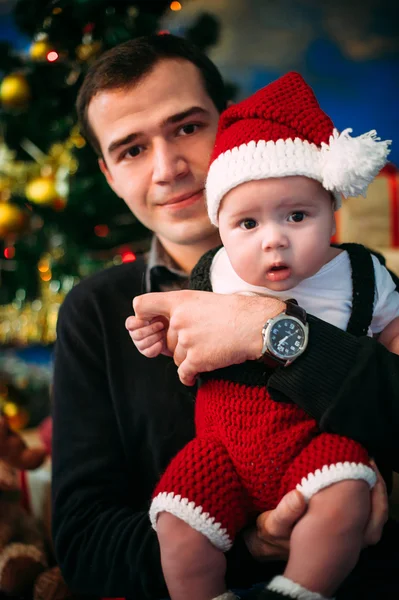 Schattige kleine jongen en zijn vader zit bij de kerstboom — Stockfoto