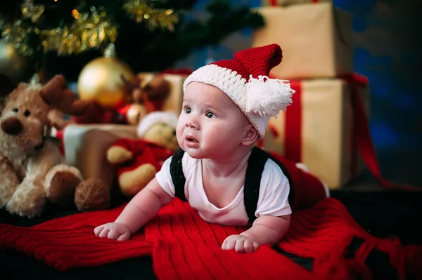 Retrato de cuento de hadas de Navidad lindo bebé vistiendo como Santa Claus en el fondo del año nuevo bajo el árbol — Foto de Stock