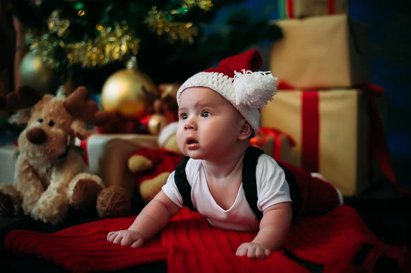 Saga porträtt av jul söta lilla bebis klädd som jultomte på nyår bakgrunden under träd — Stockfoto