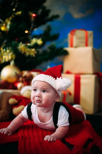 Retrato de cuento de hadas de Navidad lindo bebé vistiendo como Santa Claus en el fondo del año nuevo bajo el árbol — Foto de Stock