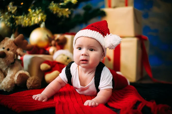 Fairy-tale portrait of Christmas cute little baby wearing like santa claus at the new year background under tree — Stock Photo, Image