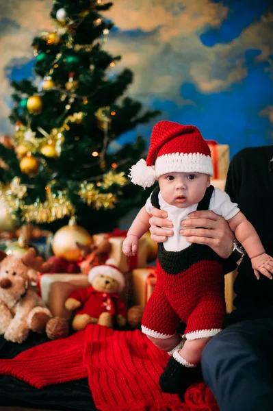 Saga porträtt av jul söta lilla bebis klädd som jultomte på nyår bakgrunden under träd — Stockfoto