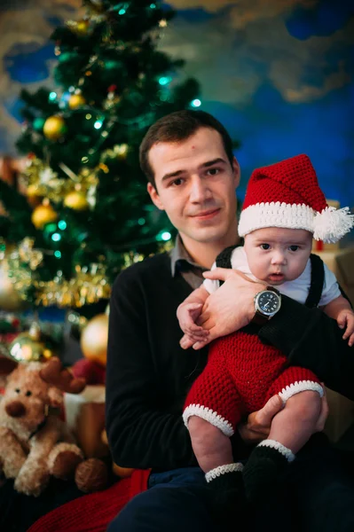 Söt liten pojke och hans pappa sitter vid julgran — Stockfoto