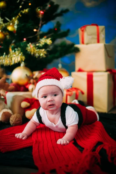 Retrato de cuento de hadas de Navidad lindo bebé vistiendo como Santa Claus en el fondo del año nuevo bajo el árbol — Foto de Stock