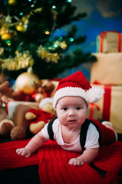Saga porträtt av jul söta lilla bebis klädd som jultomte på nyår bakgrunden under träd — Stockfoto