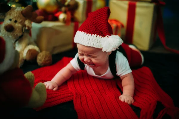 Fairy-tale portrait of Christmas cute little baby wearing like santa claus at the new year background under tree Stock Image