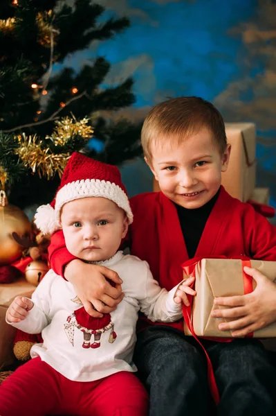 Портрет щасливих дітей з різдвяними подарунковими коробками та прикрасами. Двоє дітей розважаються вдома — стокове фото