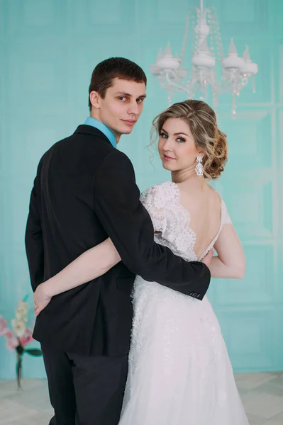 Una pareja feliz. Sesión de fotos de boda en el estudio blanco con la decoración de la boda besos, abrazos — Foto de Stock
