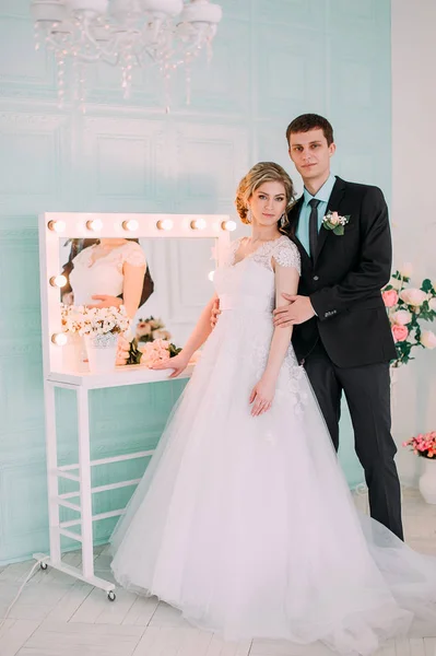 Una coppia felice. Servizio fotografico di nozze nello studio bianco con decorazioni nuziali baci, abbracci — Foto Stock