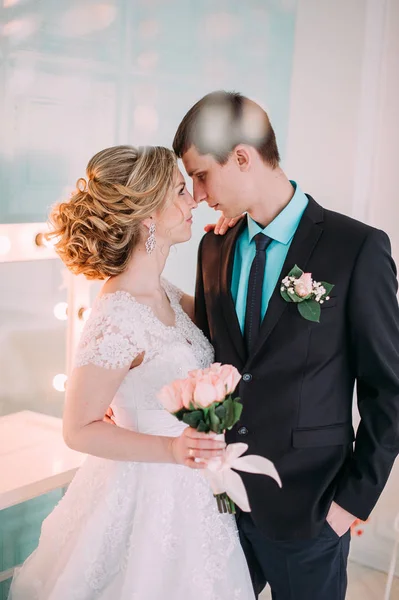 Una coppia felice. Servizio fotografico di nozze nello studio bianco con decorazioni nuziali baci, abbracci — Foto Stock