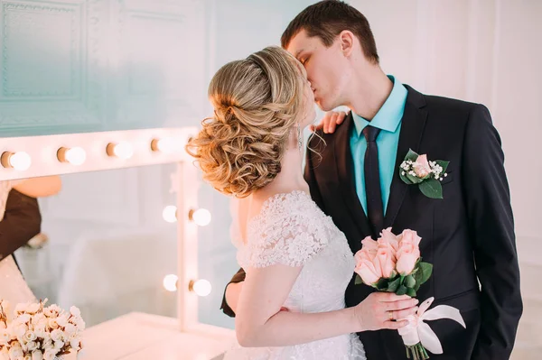 Una pareja feliz. Sesión de fotos de boda en el estudio blanco con la decoración de la boda besos, abrazos — Foto de Stock