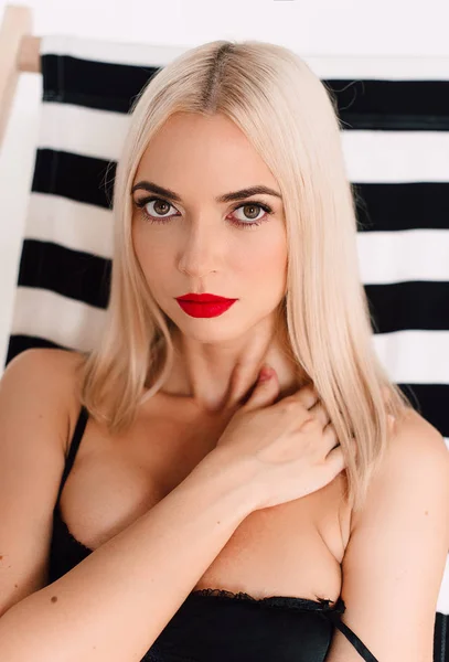 Vacker sexig kvinna i svart Underkläder, Underkläder med tan huden och röda läppar poserar på solsäng i studio på vit bakgrund. Kontrasterande retuscherade skott — Stockfoto