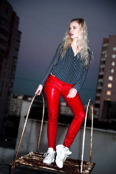 Outdoor Portret van mooie gelukkig blond Europese jongedame poseren op straat 's nachts. Model dragen van stijlvolle kleding rode broek en springen. Vrouwelijke mode. Stad nacht levensstijl. Kopiëren van ruimte. — Stockfoto