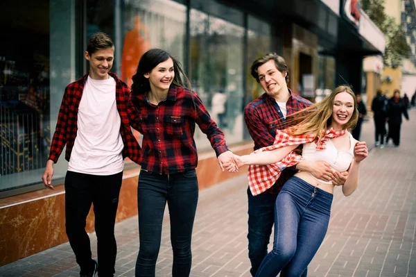 Vier gelukkig trendy jeugdvrienden wandelen in de stad, elkaar praten en lachen. Lifestyle, vriendschap en stadsleven concepten. — Stockfoto