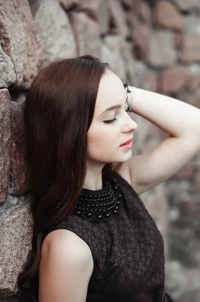 Hermosa mujer joven triste sobre un fondo de pared de piedra — Foto de Stock