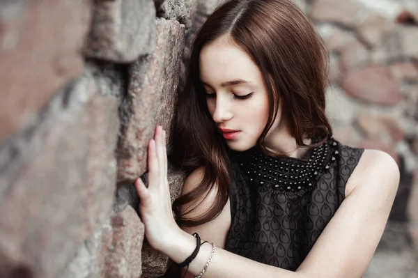 Hermosa mujer joven triste sobre un fondo de pared de piedra — Foto de Stock