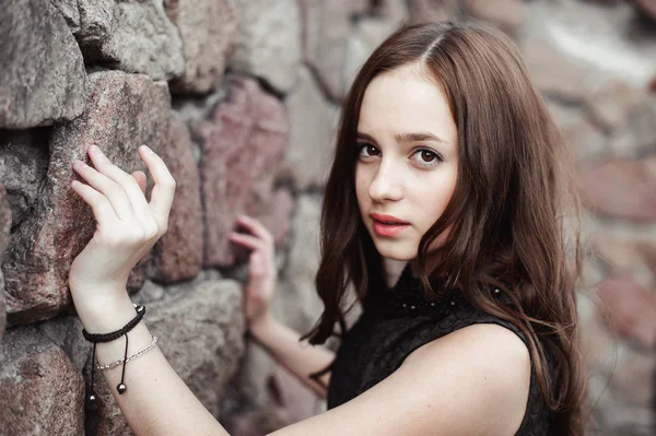 Bela triste jovem mulher em um fundo de parede de pedra — Fotografia de Stock